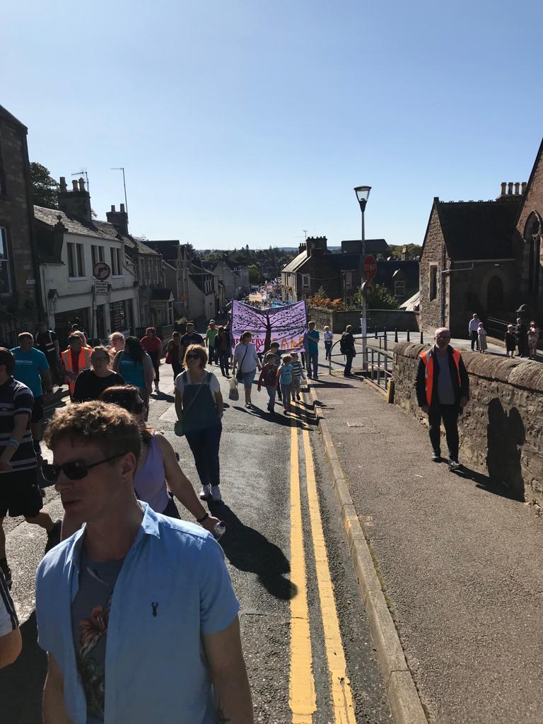 A photo taken downhill of a crowd walking along Haugh Road, heading to the Northern Meeting Park