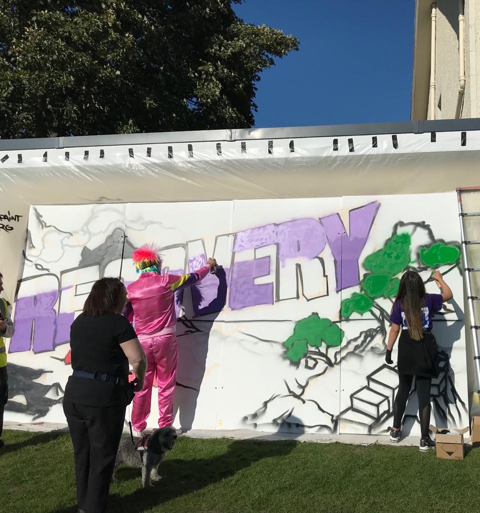 A temporary graffiti wall at the Northern Meeting Park with the word Recovery in bold letters