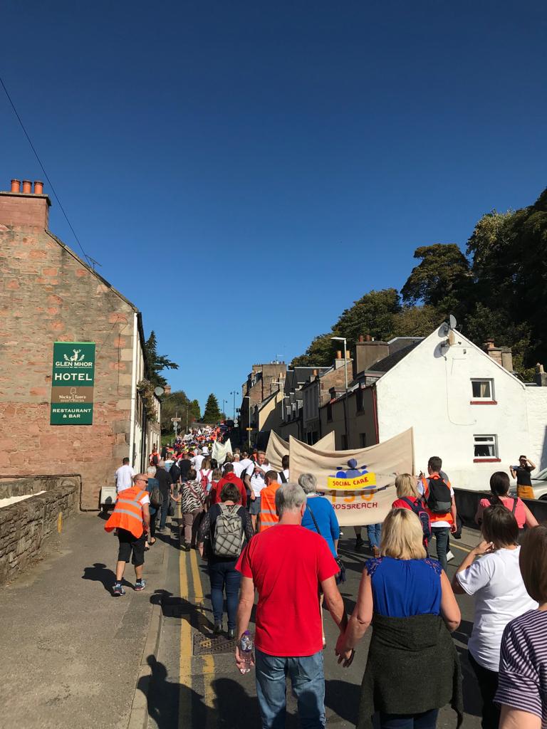 A photo taken uphill of a crowd walking along Haugh Road, heading to the Northern Meeting Park